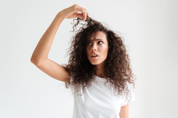 confused woman looking her frizz hair