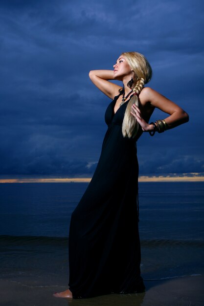 sexy woman in black gown posing sunset