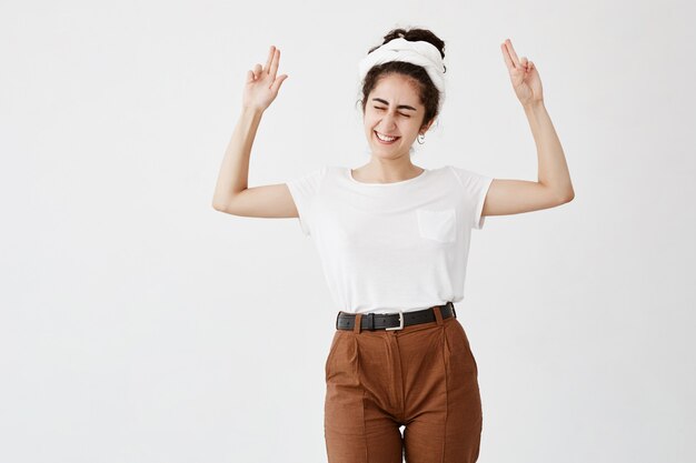 happy woman closing eye plain white tee with beige slacks look