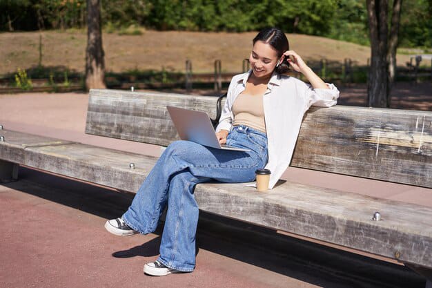 young woman posing in white tee with wide leg pants looking laptop