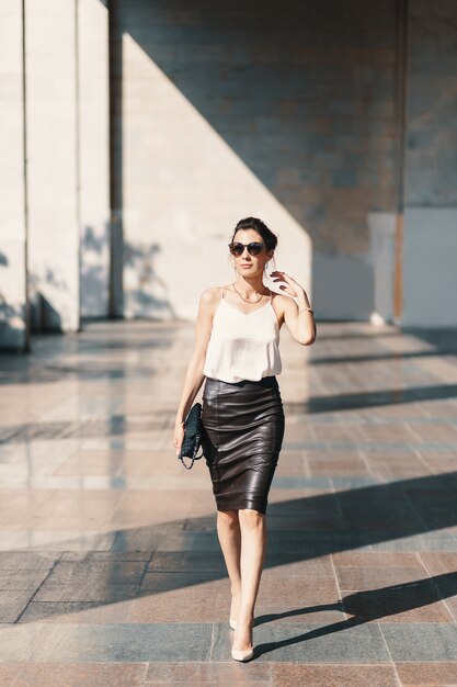 young women office look with white silk top with pencil skirt holding purse